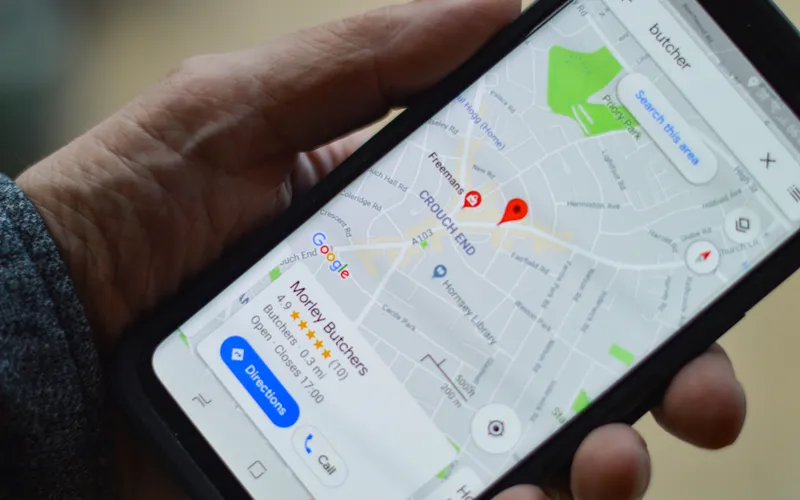 mano sujetando un movil con la pantalla mostrando un mapa de google con un marcador de ubicacion